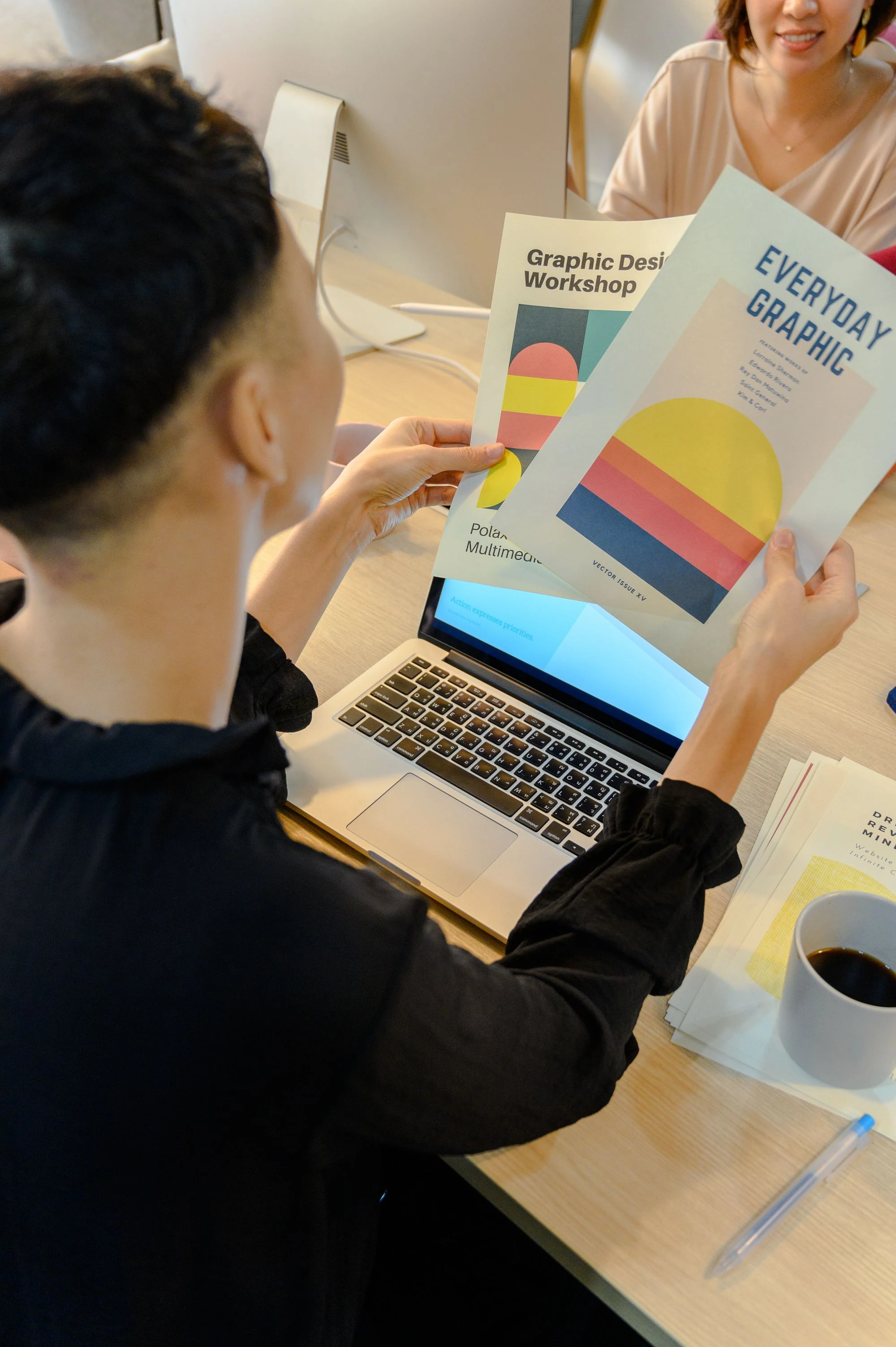 A person checking vibrant printed designs beside a laptop